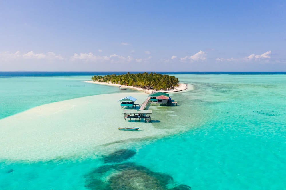 Vue aérienne d'Onok Island avec kubos sur pilotis, banc de sable et lagon peu profond